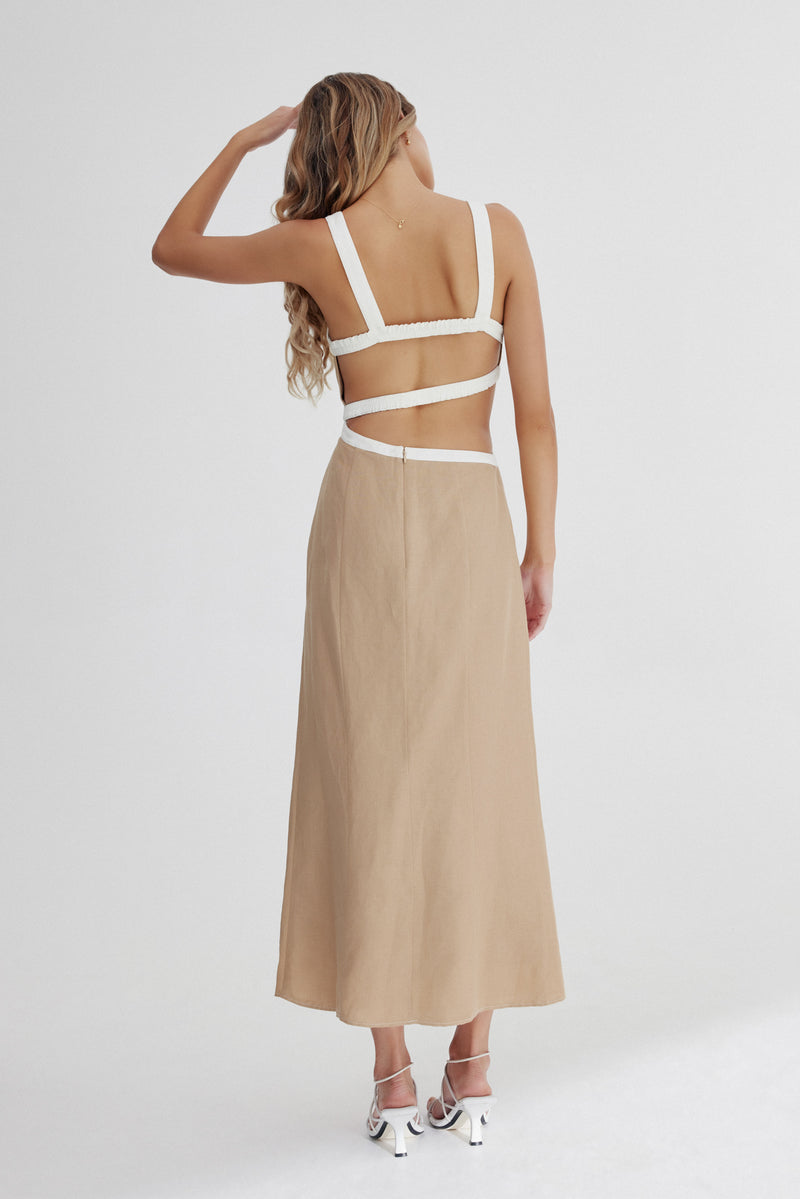 A back view of a model standing against a white background wearing Significant Other's Elena Midi Dress in Sand.